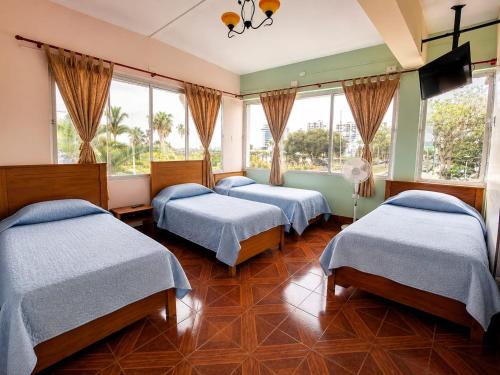 three beds in a room with windows at Hotel Illariy Wasi in Arica