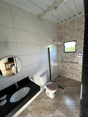 a bathroom with a toilet and a sink and a mirror at Cerrado da Canastra Chalé Quartinho simples in São Roque de Minas