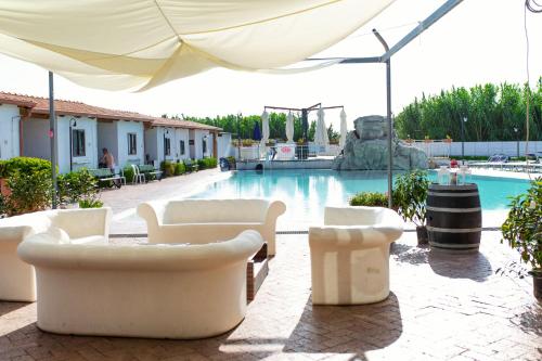 a pool with white chairs and an umbrella at Residence Arco delle Rose in Agropoli