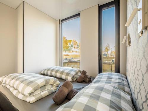 two beds in a room with large windows at Marina Sunrise in Volendam