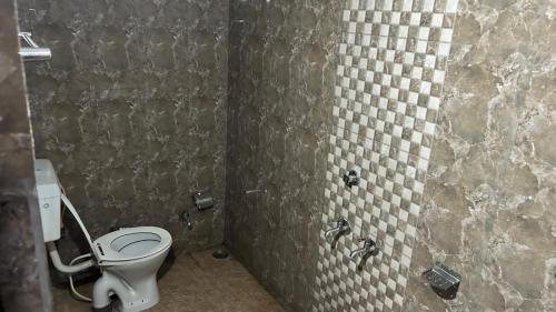 a bathroom with a toilet and a tiled wall at RR palace in Pachmarhī