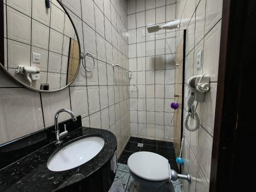 a bathroom with a sink and a toilet and a mirror at Loft Carminatti in Cacoal
