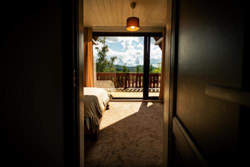 a bedroom with a bed and a view of a balcony at Casa Sunetul Padurii din Belis Apuseni in Călăţele