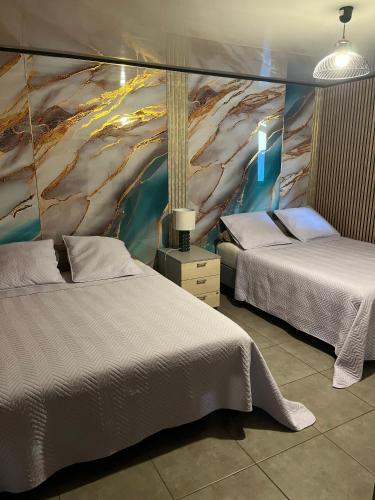 a bedroom with two beds and a painting on the wall at La villa d'Isalya in Sainte-Suzanne