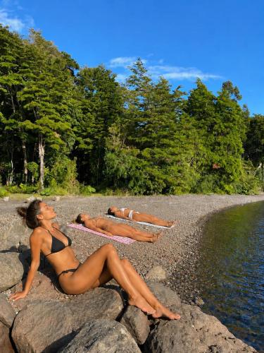 two women in bathing suits laying on rocks on a beach at Calma Lodge in Puerto Clocker
