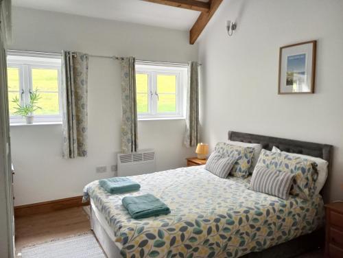 a bedroom with a bed and two windows at Vineyard Barns Gower in Swansea