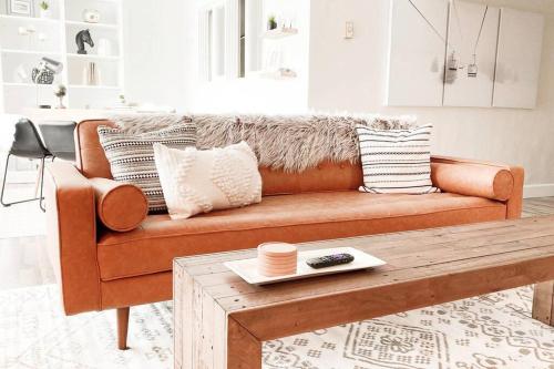 an orange couch in a living room with a coffee table at Modern Mountainside Chalet in Steamboat Springs