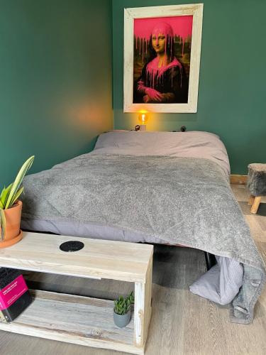 a bedroom with a bed with a table and a painting at Self contained cabin - The VenU in Bristol