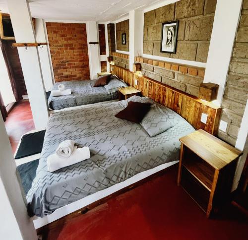 a bedroom with two beds and a brick wall at La Misión Hotel Chignahuapan in Chignahuapan