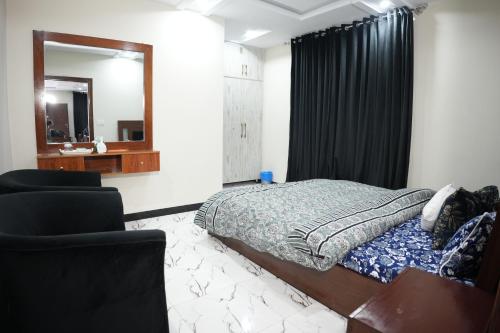 a bedroom with a bed and a mirror and a chair at Royal Cottage in Murree in Murree
