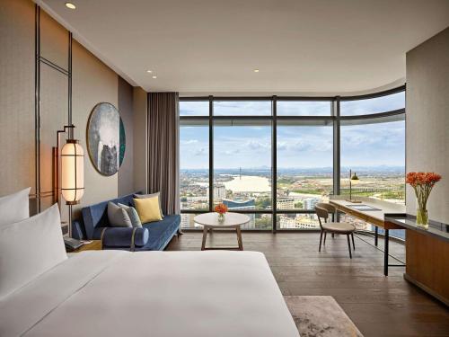a bedroom with a large bed and a living room at Pullman Hai Phong Grand Hotel in Hai Phong