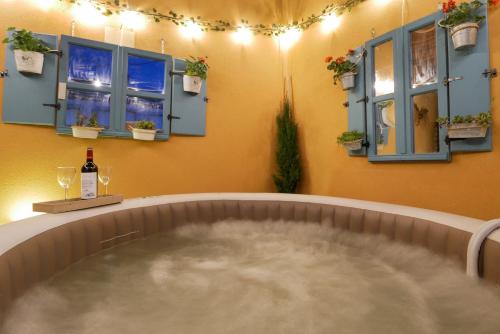 a hot tub in a room with windows and a bottle of wine at Casas Rurales Florentino in Robledillo