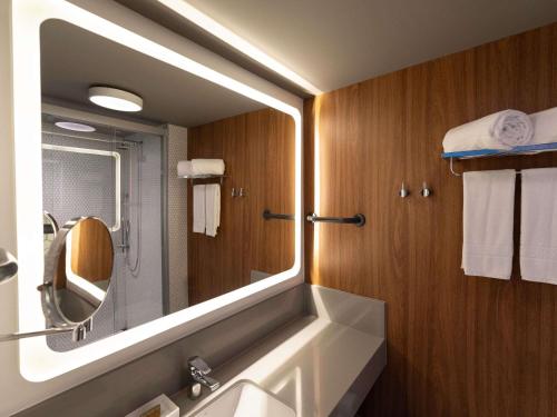 a bathroom with a large mirror and a sink at Novotel Recife Marina in Recife