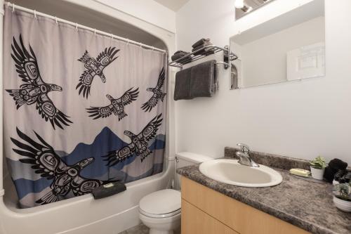 a bathroom with a shower curtain with birds on it at The Hitching Post Motel in Pemberton