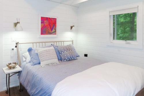 a white bedroom with a bed and a window at Lake Winni Cottage in Moultonborough