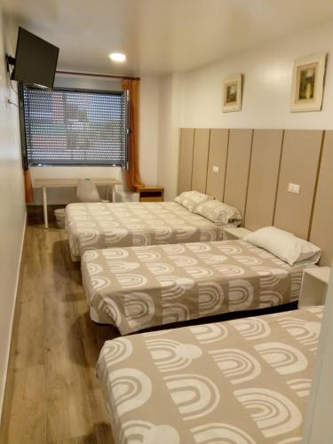ein Hotelzimmer mit drei Betten und einem Fernseher in der Unterkunft Hotel Skyline Boadilla in Alcorcón
