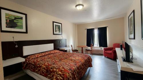 a hotel room with a bed and a red couch at Studio 7 By Capital O Killeen I-14 in Harker Heights