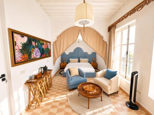 a room with a bed and two chairs and a table at Riad Chama in Essaouira