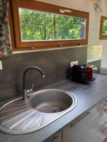 a sink in a kitchen with a window above it at Tiny House Insolite avec Escape Game in Chanzeaux