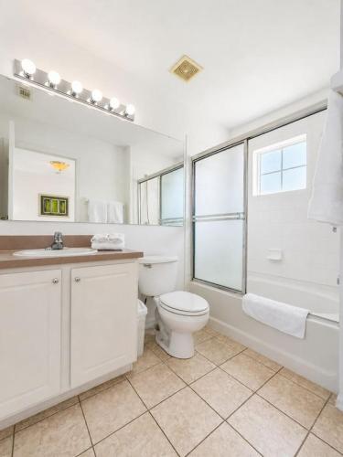 a white bathroom with a toilet and a window at See you in Orlando in Kissimmee