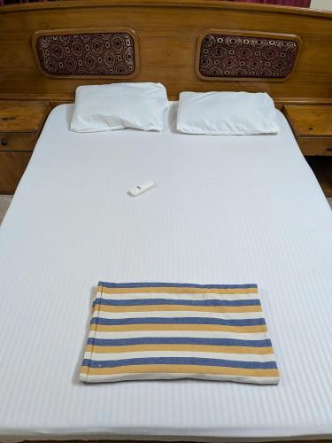 a bed with two pillows and a striped towel on it at JUST WALKING DISTANCE FROM Temble in Guruvāyūr