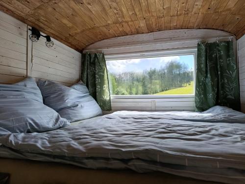 a bed in a room with a window at Útulná Maringotka in Dolní Město