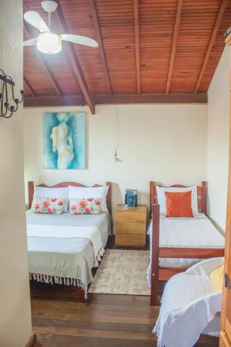two beds in a room with wooden ceilings at CHALÉ ADOBE in Carrancas
