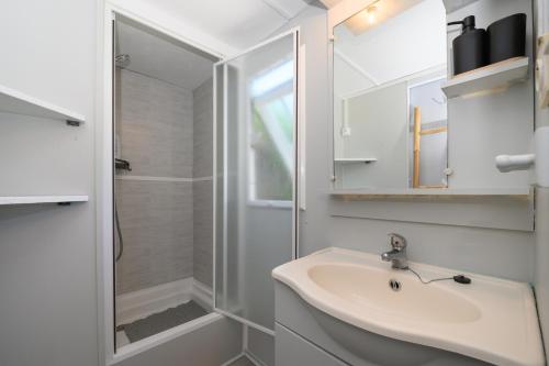 a white bathroom with a sink and a shower at La Dune d’Erdeven in Erdeven