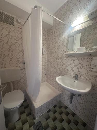 a bathroom with a white sink and a toilet at Hotel Zagreb in Crikvenica