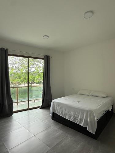 a bedroom with a bed and a large window at Hotel Kleos in Cárdenas