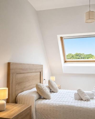 a white bedroom with two beds and a window at Airtegal Atico Mar de Cedeira in Cedeira