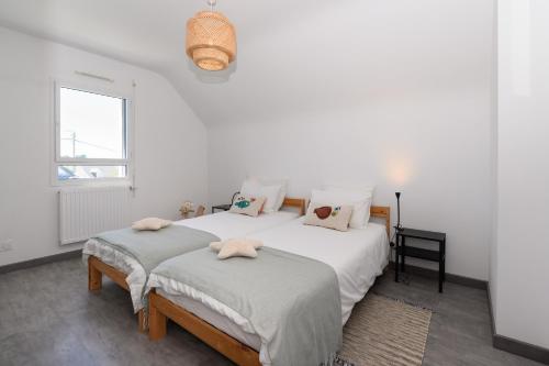 two beds in a room with white walls and a window at Maison de vacances Plouharnel 3star in Plouharnel