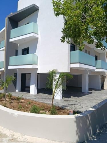 a white building with blue balconies and a tree at Olympus Hospitality Rhodes in Rhodes Town