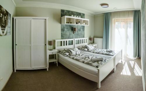 a bedroom with a large white bed and a desk at Villa Corvina in Győrújbarát
