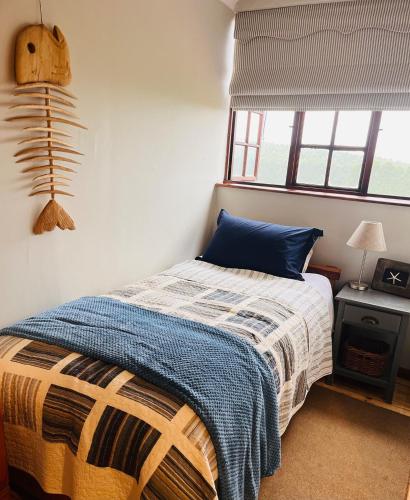 a bedroom with a bed with a blue blanket and a window at The Orchard in Hilton