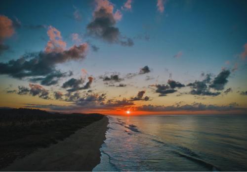 a sunset over a beach with the ocean at Casa Sal by Tasman in Puerto Escondido