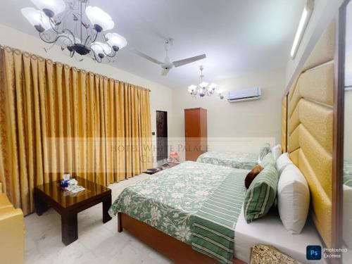 a bedroom with a bed and a chandelier at Hotel White Palace Clifton in Karachi