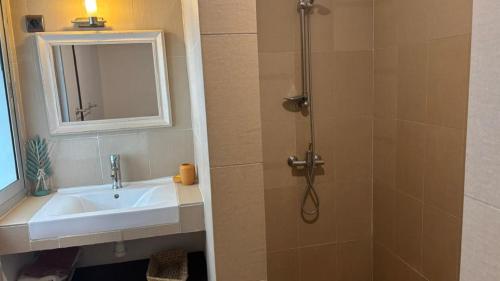 a bathroom with a sink and a shower with a mirror at Chambres d'hôtes WAIMEA in Abidjan