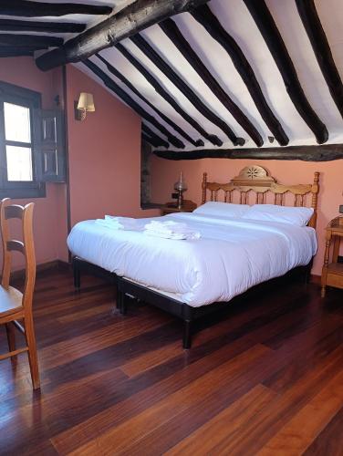 a bedroom with a large bed with white sheets at Posada de Candelario in Candelario