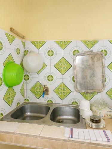 a kitchen sink with a green and white tiled wall at Marchica House in Nador