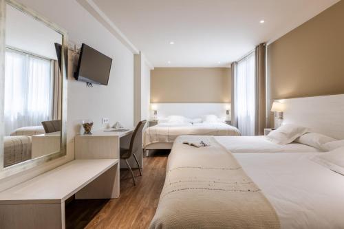 a hotel room with two beds and a desk at Hotel La Terraza in Miño