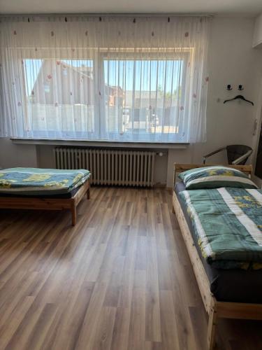 two beds in a room with wooden floors and a window at Sylbacher Gästehaus in Bad Salzuflen
