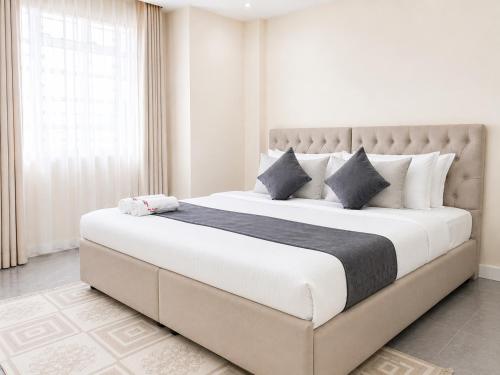 a bedroom with a large bed with white sheets and pillows at Naka Executive Suites With Balcony, Amazing View of Lake Nakuru, GYM in Nakuru