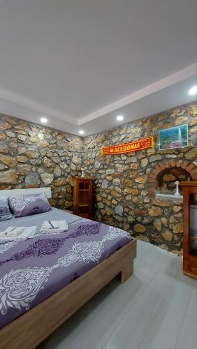 a bedroom with a bed and a stone wall at Guest House Nadol SUP and Bikes included in Ohrid