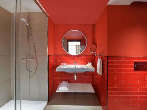a red bathroom with a sink and a mirror at IBIS STYLES KINSHASA in Kinshasa