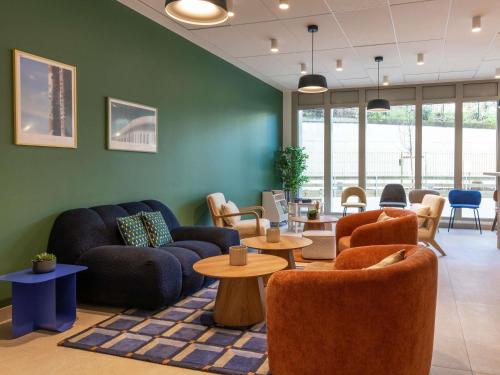 a living room with couches and tables and chairs at Adagio Access Paris Nanterre in Nanterre