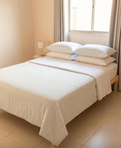 a bed with white sheets and pillows in a bedroom at Villa S in Ouagadougou