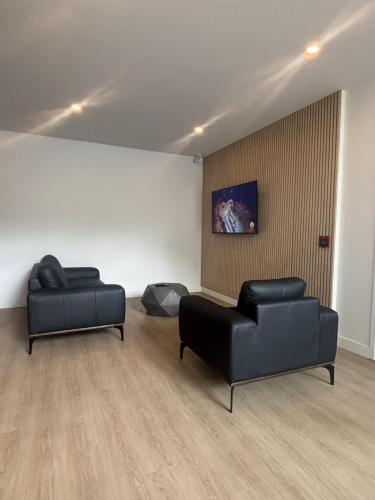 zwei schwarze Ledersessel und eine Couch in einem Zimmer in der Unterkunft Hotel W Des Cantons in Weedon-Centre