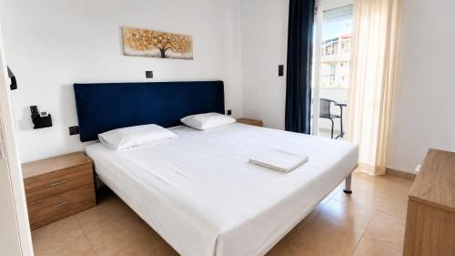 a bedroom with a large white bed with a blue headboard at Aleka Apartment in Kos