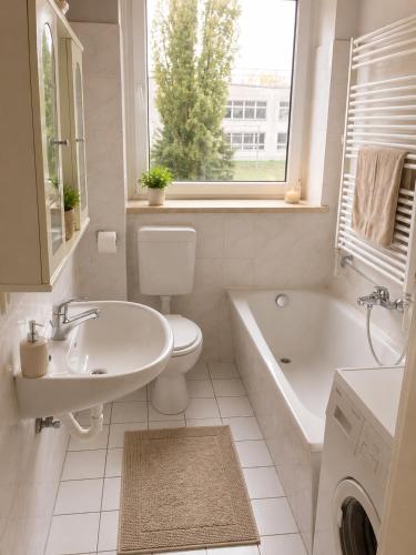 a white bathroom with a sink and a toilet and a tub at Apartmenthaus in der Nähe Wolfsburg und VW in Oebisfelde